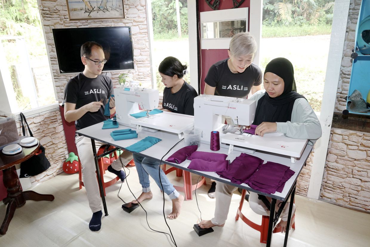 Suraya (right) sewing the lavender eye pillow under the tutelage of Lim (second right) while Antik As (second left) and Wee getting the fabric sorted out. — ART CHEN/The Star