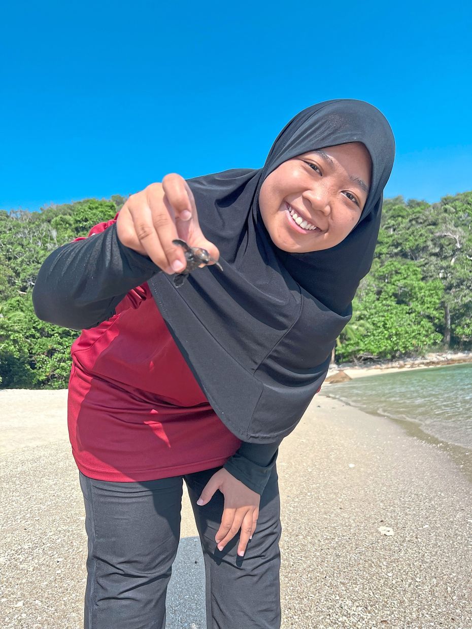 USE THIS ONLYThe writer with one of the turtle hatchlings. — MIZAN KAMALINA JUMMAT