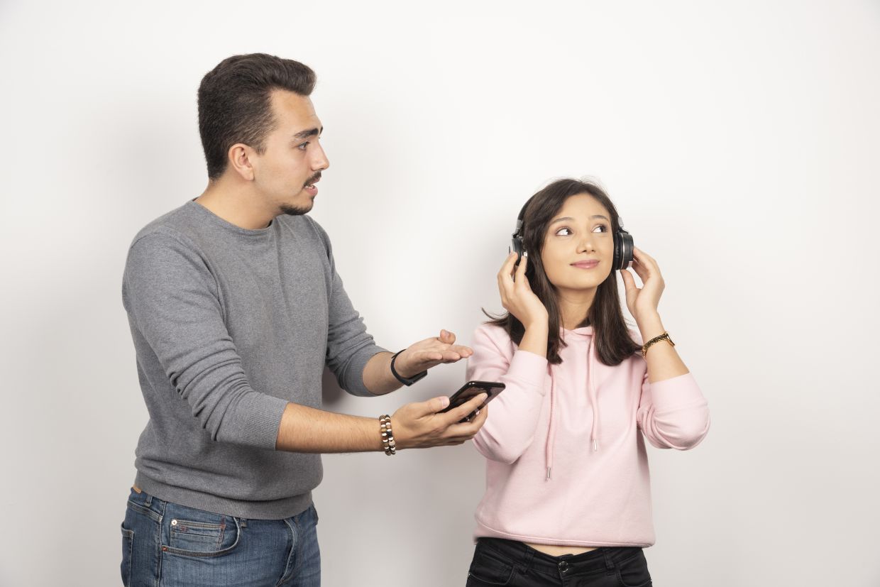 Young man trying to get reach out woman for looking at his phone. High quality photo