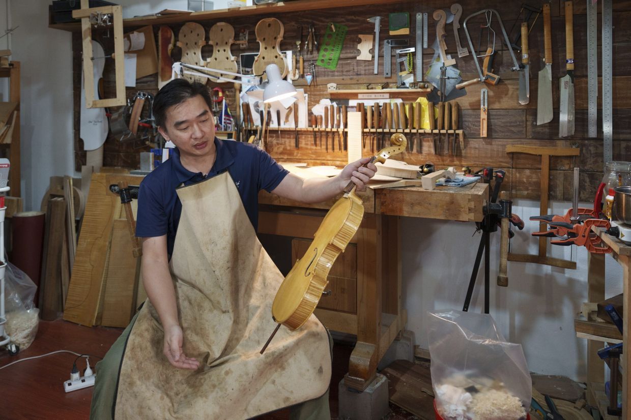 Malaysian luthier Tan Chin Sang examines a handcrafted violin at his workshop on the outskirt of Kuala Lumpur, Malaysia, Thursday, July 2, 2025. (AP Photo/Vincent Thian)
