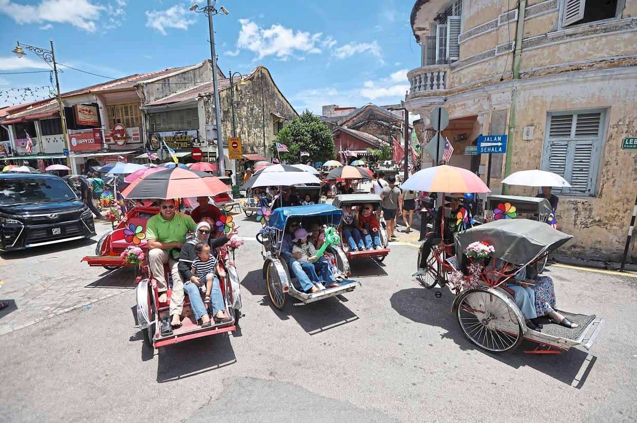Group of tourists on trishaw tour along Armenian Street during school holidays in George Town, Penang. (September 15, 2024) —ZHAFARAN NASIB/The Star