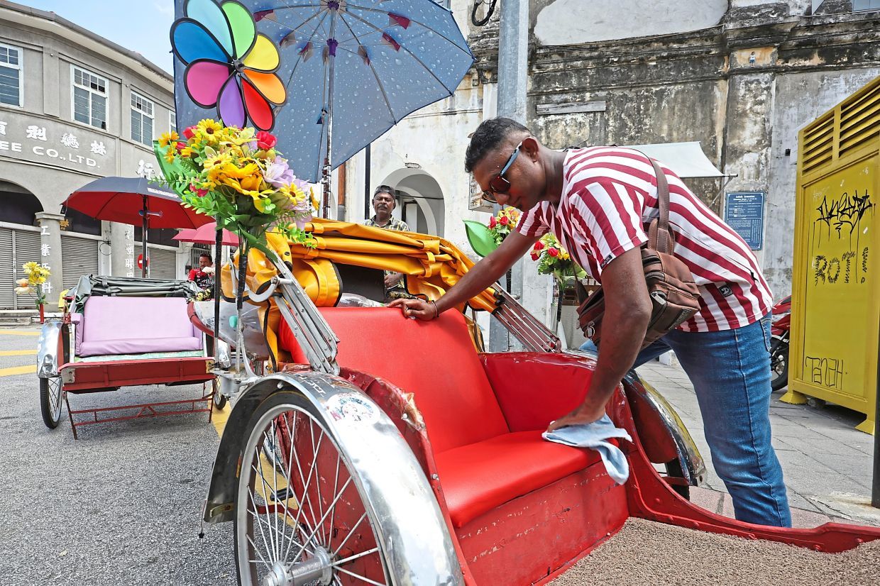 (BRIEF CAPTION): Trishaw rider M. Ganapati, 37, wiping the seat while he waiting for customer at Armenian Street in George Town, Penang.( JUNE 17, 2025)¡ªCHAN BOON KAI/The Star