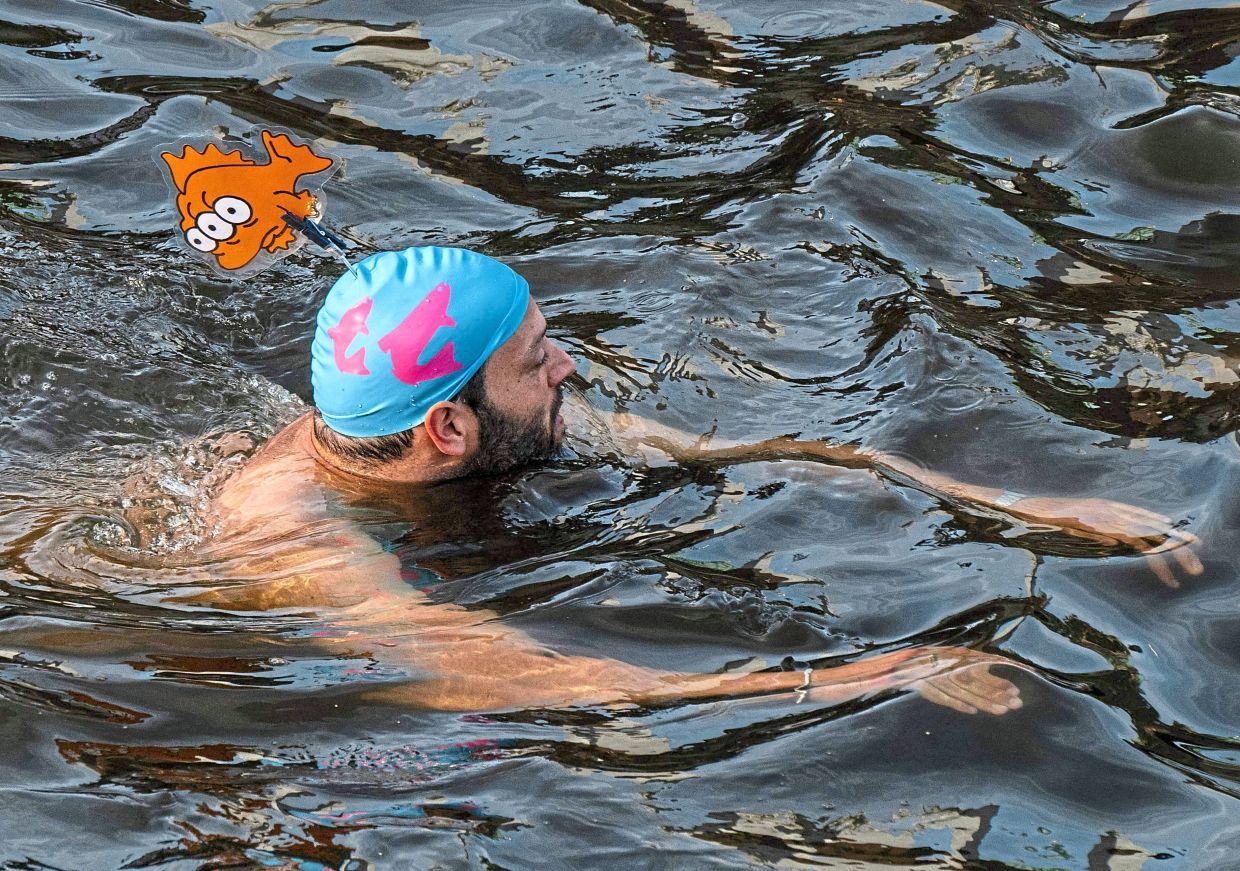 A swimmer bathes in the Spree canal during a demonstration to mark the 100th anniversary of a ban on swimming in the Spree river, in Berlin on June 17, 2025. The demonstrators are pleading for a lifting of the ban. (Photo by John MACDOUGALL / AFP)