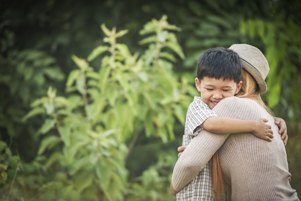 Portrait of mother and son happy cuddle together in the park. Family concept.