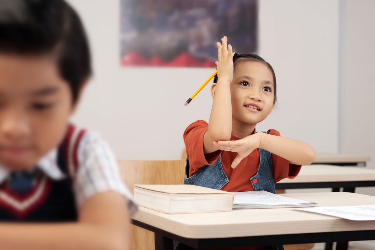 Smart little schoolboy is willing to answer a question of teacher