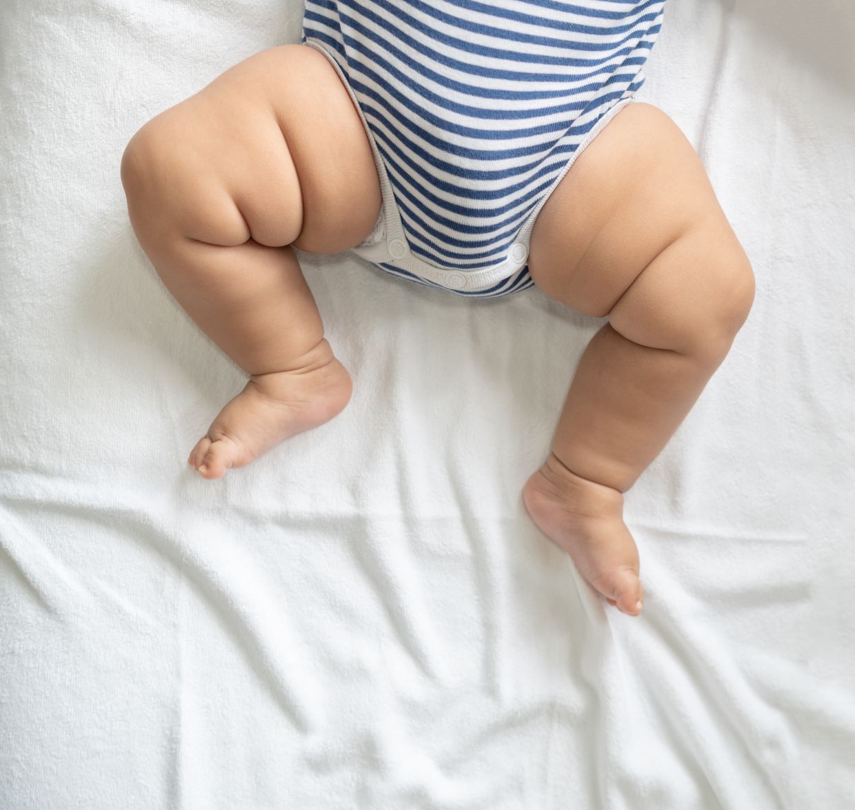 Baby feet in white bed. Selective focus.