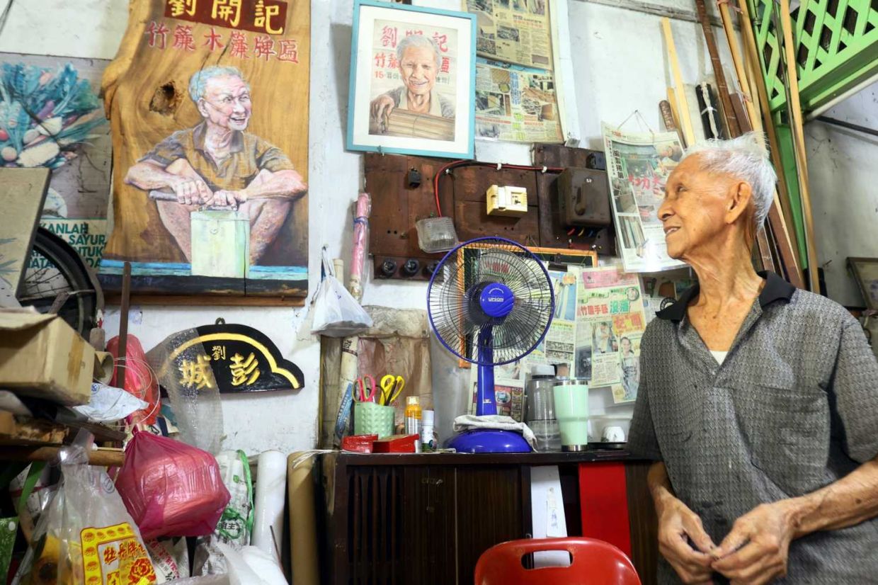 Chick blinds weaver Lau Chee Wah,89looking on his potraiture drawn by a German artist that were hung at his shop..(25th August 2025)--RONNIE CHIN/The Star