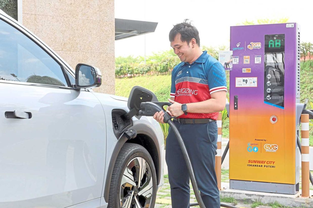 Muhammad Nur Sadiqin Mohd Khusni charging his electrical vehicle (EV) with Gentari's charging station. — THOMAS YONG/The Star