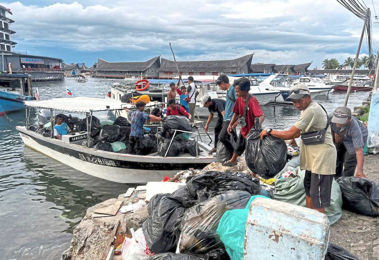 Community members unloading waste at the Semporna jetty after a collection drive on Mabul Island, as part of the district's cleanliness initiative led by locals.