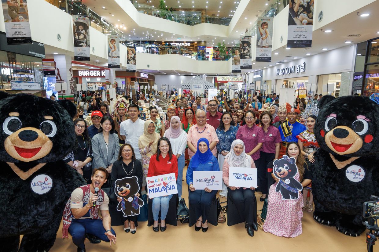 A group photo featuring Tourism Malaysia Deputy Director General (Planning) Datin Rafidah Idris (blue shirt) and Star Media Group Senior General Manager of Client Brand Marketing Sharon Lee Li Wei (red shirt) together with event sponsors, exhibitors and cultural performers during the launch of the Star Karnival Cuti-Cuti Malaysia at Plaza Merdeka in Kuching. The vibrant showcase marks a strong public-private collaboration to promote domestic tourism, featuring cultural displays, travel packages and family-friendly attractions aimed at encouraging Malaysians to explore the beauty of their own country.— ZULAZHAR SHEBLEE/The Star