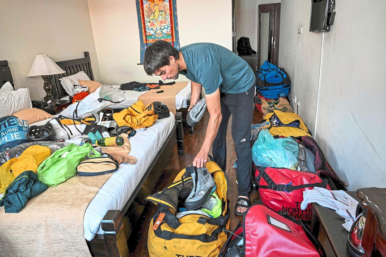 In this photograph taken on August 31, 2025, French mountaineer Benjamin Védrines sorts his climbing gear after an interview with AFP in Kathmandu. Nepal's mountains including Everest have long drawn climbers from across the world, but a growing community is exploring hidden summits promising solitude and the chance to be first to the top. The Himalayan nation is home to eight of the world's 10 highest peaks and welcomes hundreds of climbers every year, making mountaineering a lucrative business. (Photo by Prakash MATHEMA / AFP) / To go with 'Nepal-Mountaineering', FOCUS by Paavan MATHEMA