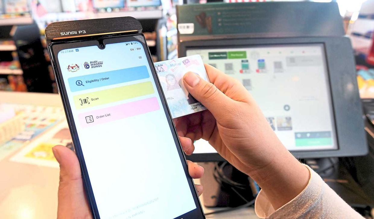A petrol station worker checkingMYkad of acustomer eligibility ahead of the Ron95 subsidy programme at Petronas station in Kuala LUMPUR21.- AZHAR MAHFOF/The Star