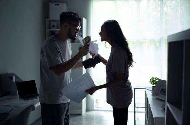 Asian couple arguing about money at home, husband and wife shouting in a hard quarrel by their many debts at home, financial family problems concept.
