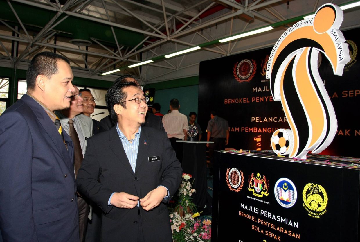 From Left: KETUA PENGARAH MSN YBHG DATUK ZOLKPLES EMBONG; TIM MENTERI BELIA & SUKAN MERANGKAP PENGERUSIS J/K PEMBANGUNAN BOLA SEPAK NEGARA YB DATUK RAZALI HJ IBRAHIM looking at the logo of bengkel penyelarasan bola sepak.
