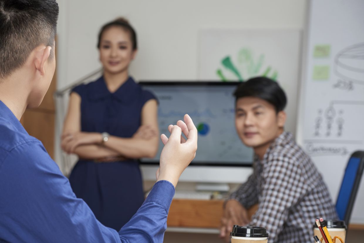 Cropped image of young businessman telling his idea to coworkers at meeting