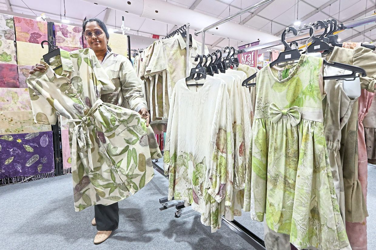 Eco-print batik artisan M. Ratha, 54, holding a dress with leaf-patterned batik designs. — THOMAS YONG/The Star