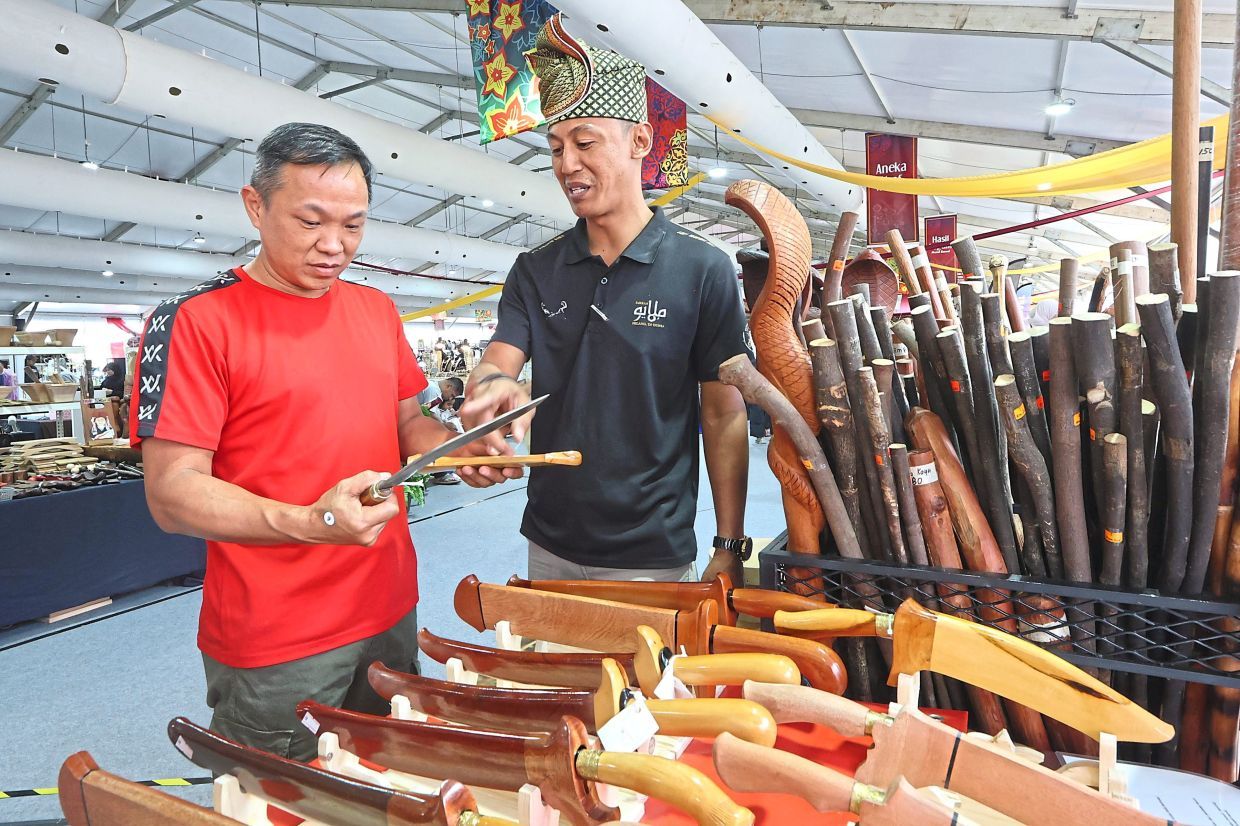 Woodcraft maker Mohd Herman M. Surib, 40, explaining to a visitor about his keris and other products. — THOMAS YONG/The Star