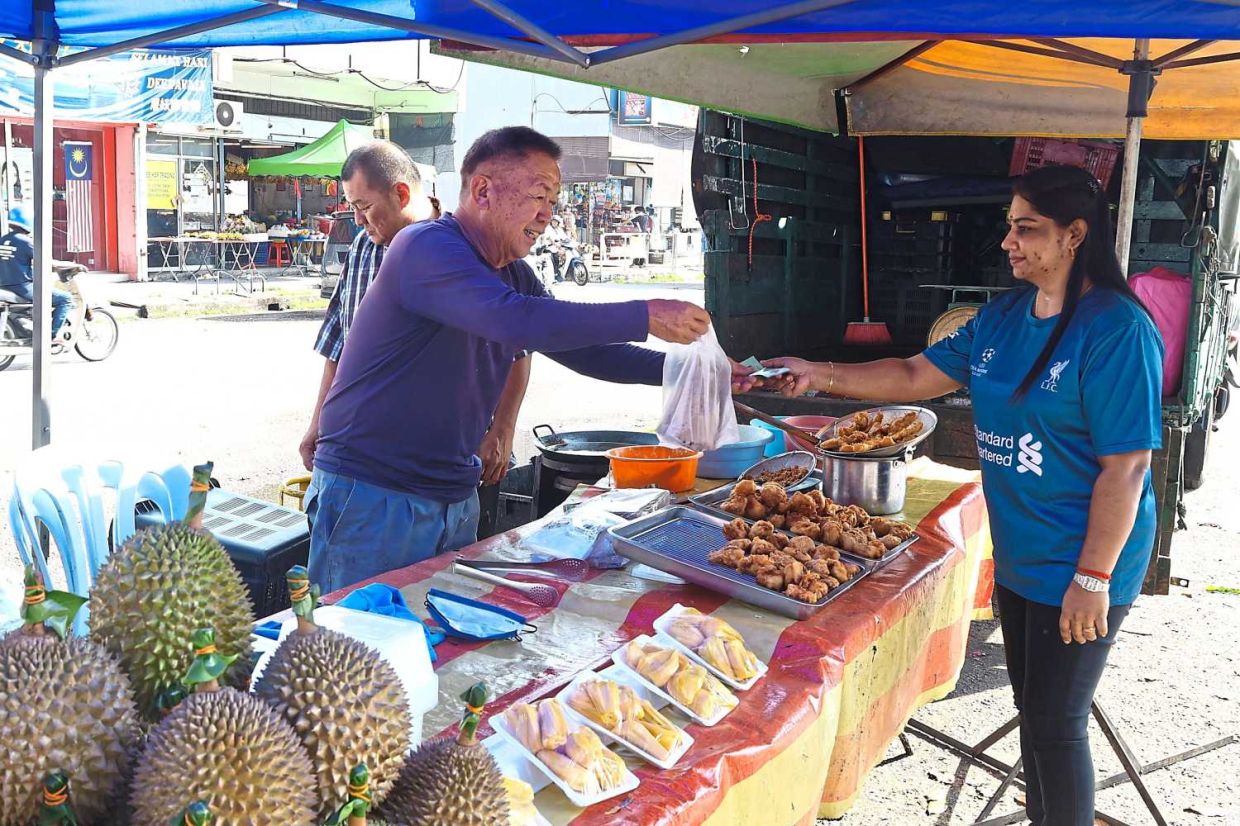 M. Sarania purchasing fried cempedak fromChee Chin Yoon
