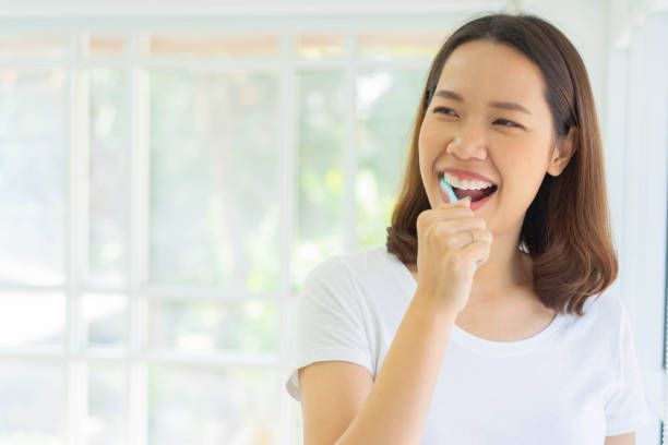 close up young asian woman using toothbrush to brushing teeth at bathroom in the morning fro healthy and routine life concept