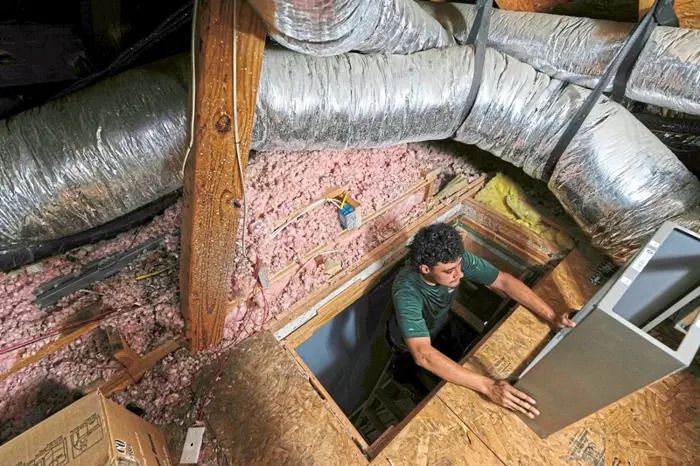 FILE - An installer climbs into an attic with parts of a new HVAC system that was installed in a residential home in Fate, Texas, on Wednesday, July 30, 2025. (AP Photo/Tony Gutierrez, File)